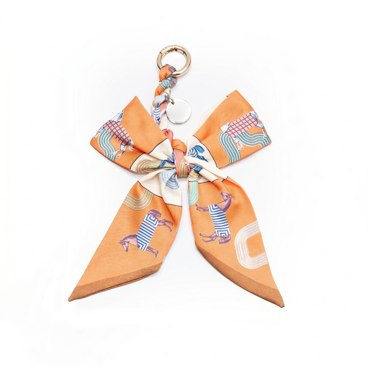 Orange horse print fabric bow bag charm on a gold clasp