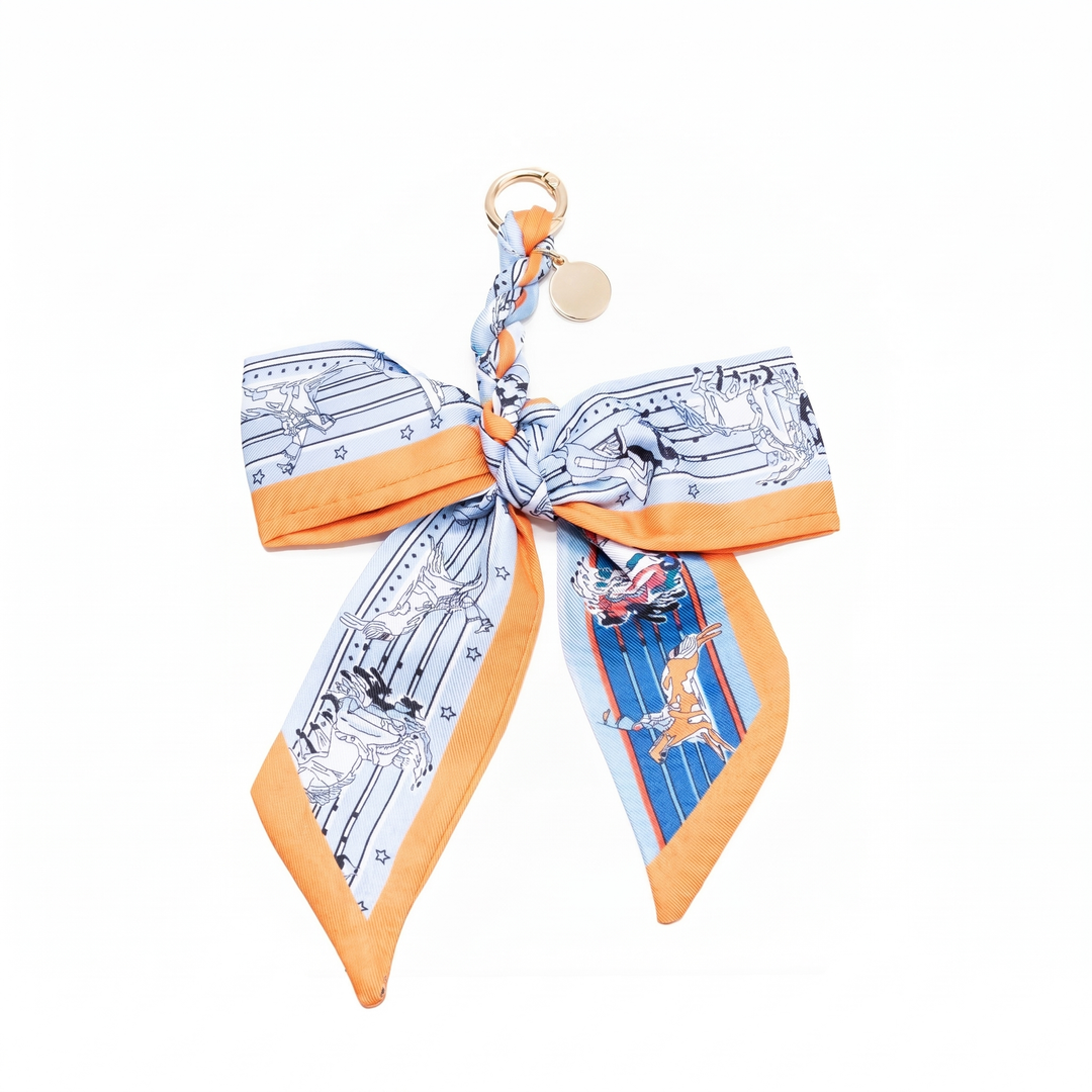 Light blue and orange print fabric bow bag charm on a gold clasp