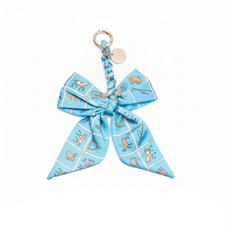 Light blue equestrian print fabric bow bag charm on a gold clasp