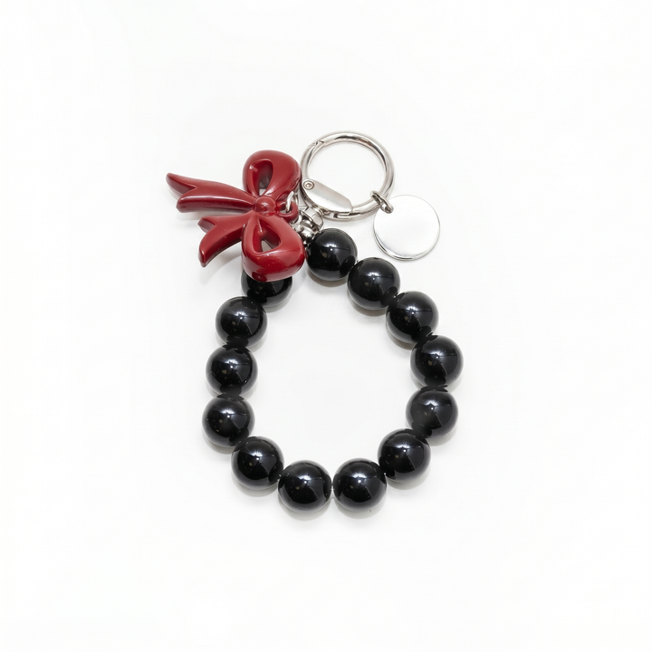 Black beaded loop bag charm with a glossy red bow
