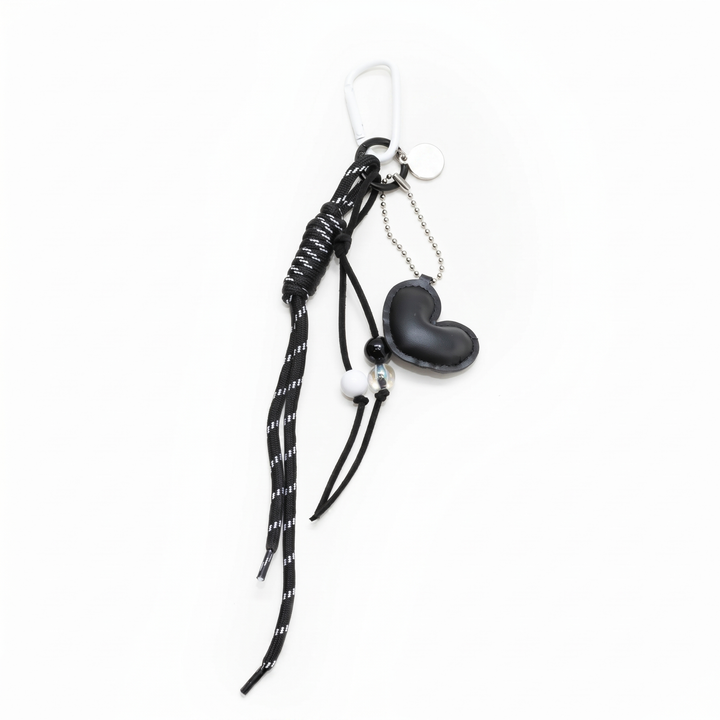 Black padded heart bag charm with a beaded cord