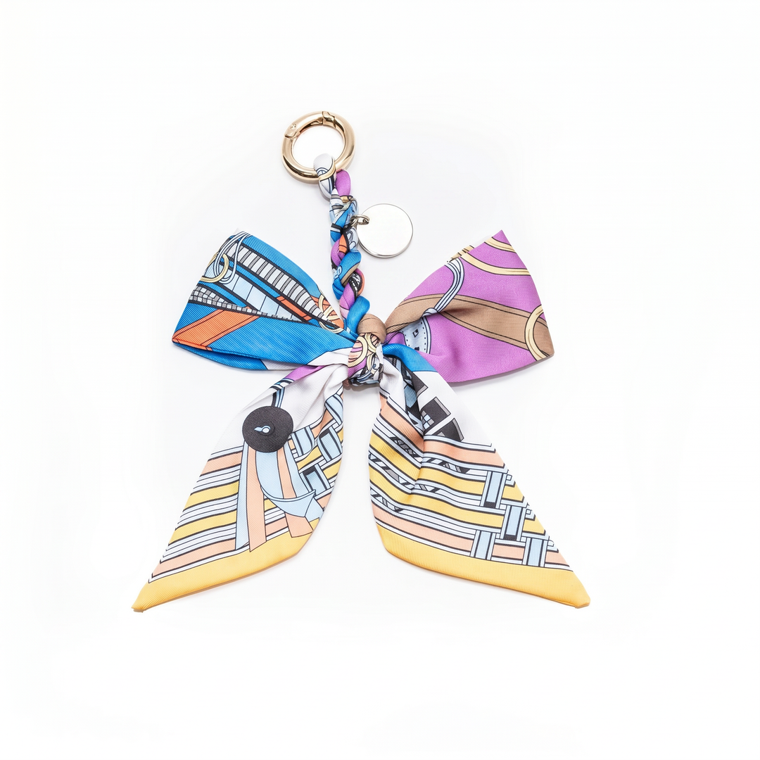 Purple multicolour print fabric bow bag charm on a gold clasp