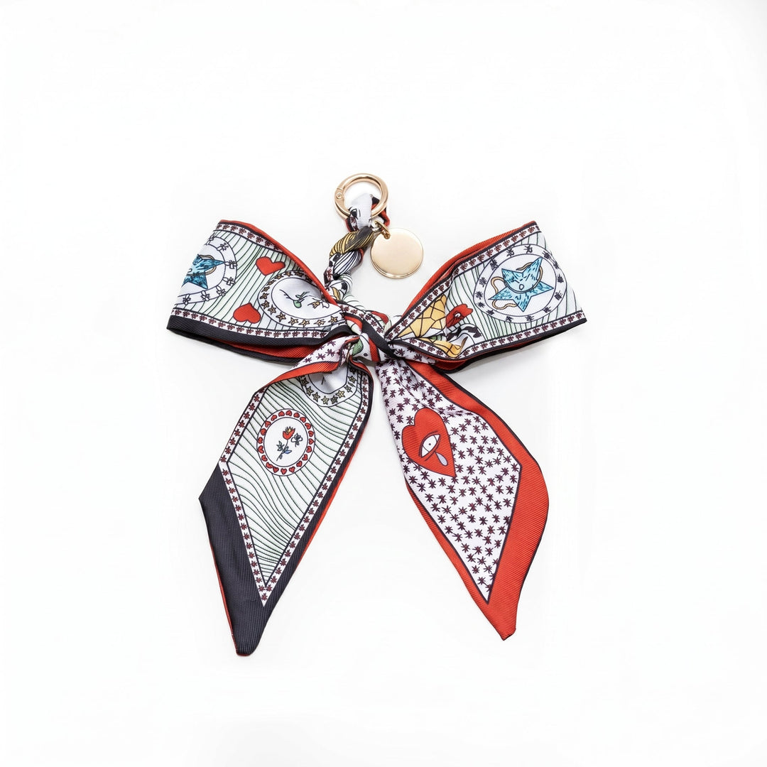 Red and white heart print fabric bow bag charm on a gold clasp